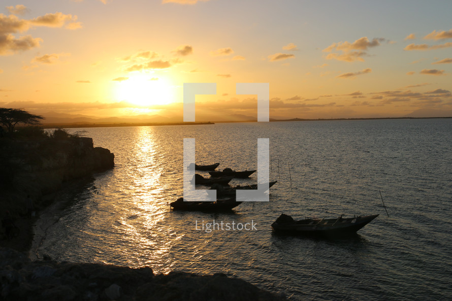 boats along a rocky shore in Haiti at sunset 