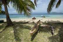 Boats on beach and kayak under the palm trees.
