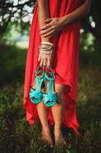 a woman in a red dress holding her turquoise shoes 