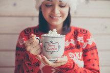 a woman in a Santa hat holding mug of hot cocoa 