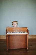 toddler girl and a child's piano 
