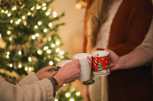 Women put their Christmas cups together in a toast.