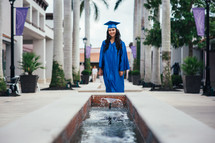 teen girl standing in her cap and gown at graduation 