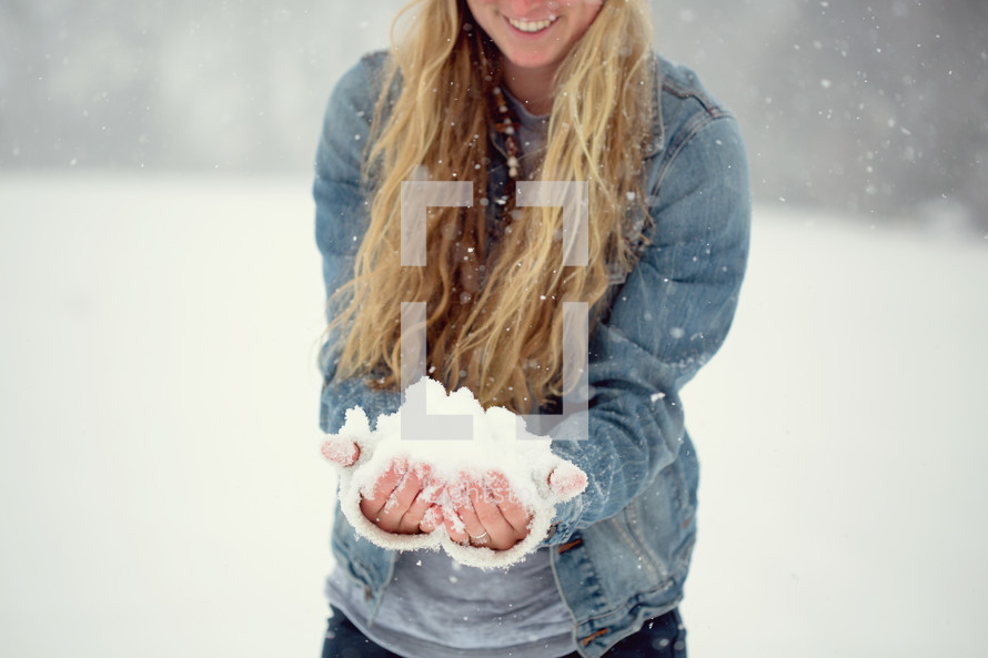 a young woman with a hand full of snow 