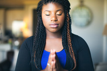 African American woman with closed eyes and praying hands 