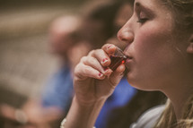 woman drinking wine from a communion cup 