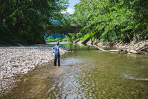 a little boy standing in a river 