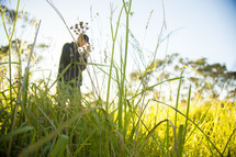 man standing outdoors in tall grass with praying hands 