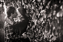 couple kissing against a wall covered with ivy