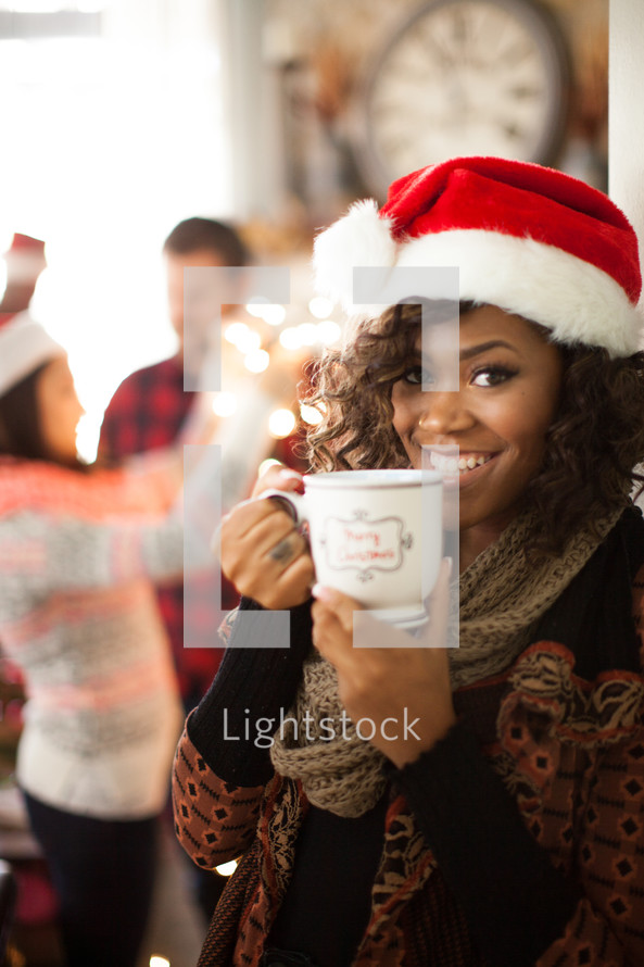 A young woman wearing a santa hat and holding a cup of coffee