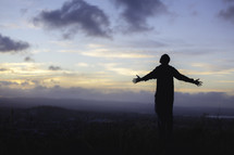 a man standing on a mountaintop with outstretched arms 