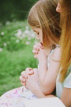 Mother and daughter praying outside.