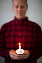 A man holding a lit candle for a candlelight service