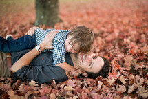 father and son hugging in fall leaves 
