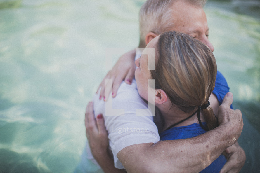 pastor hugging a woman after her baptism in water 