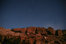 stars in a night sky above red rock 