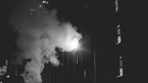 Steam coming from city buildings at night.