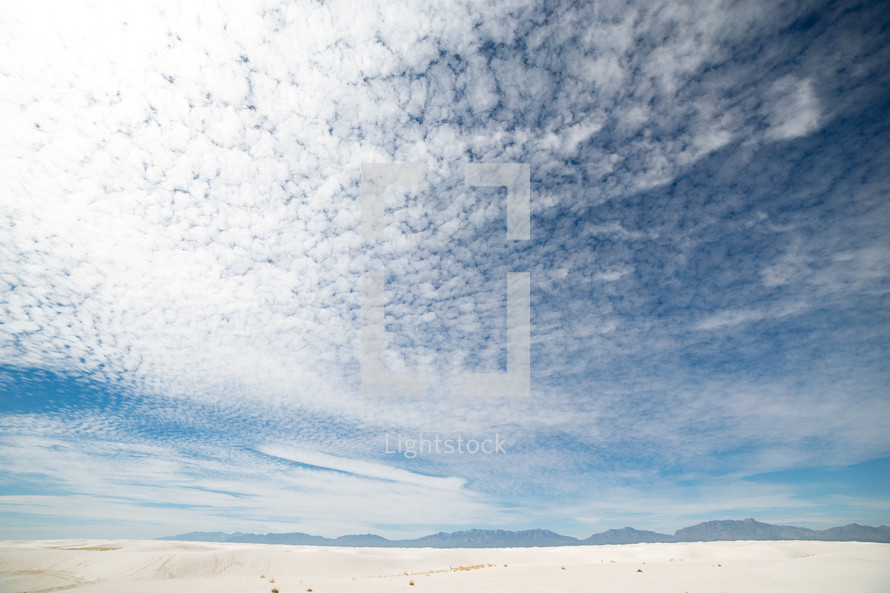 clouds in a blue sky over a sandy desert 