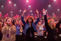 women with hands raised in praise during a worship service 