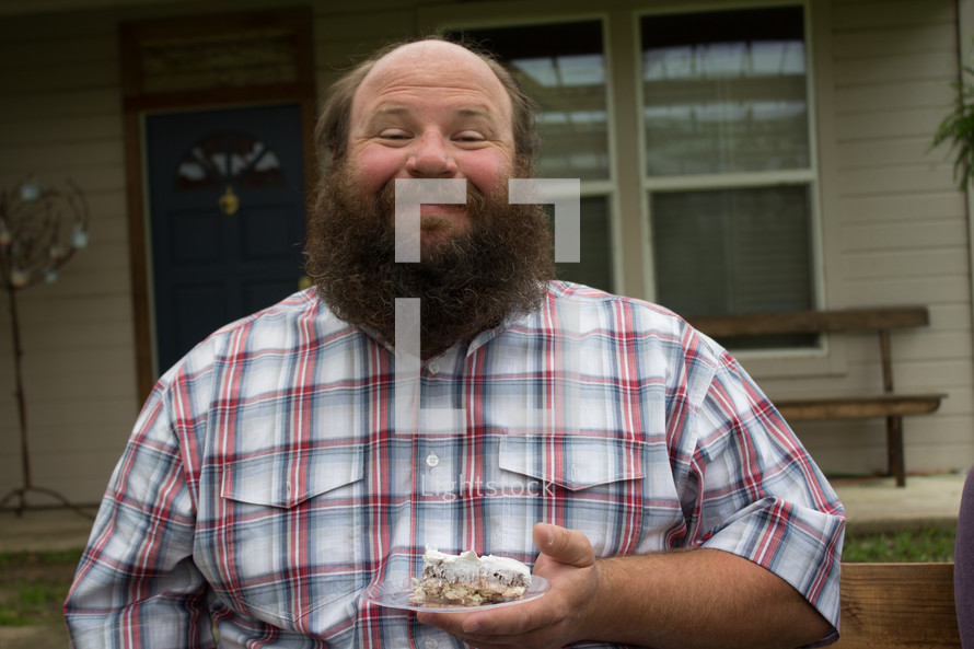 man with a beard holding a piece of cake 