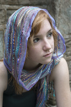 Girl with scarf on her head looking into the distance.