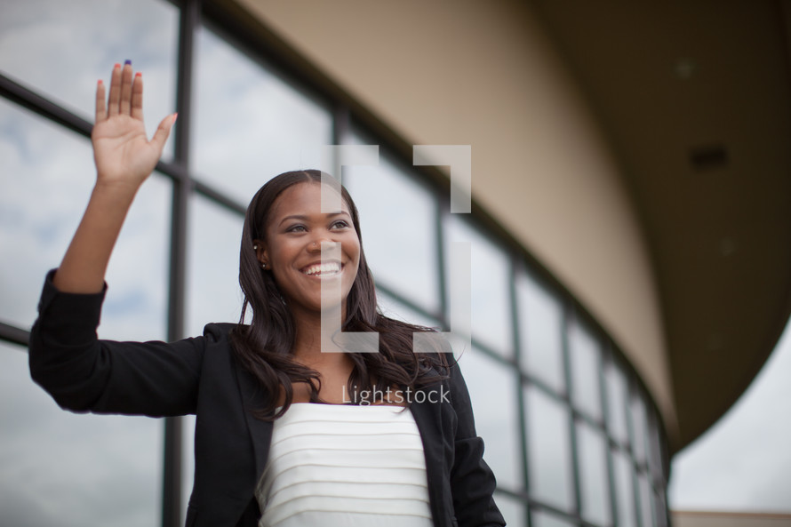 African-american woman waving to others at the entrance of a church 