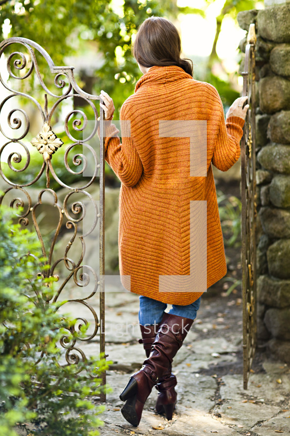 A young woman in a sweater standing between gates orange