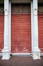 red stained wood planks on an exterior wall and white columns