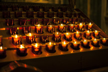 Rows of lit votive candles.