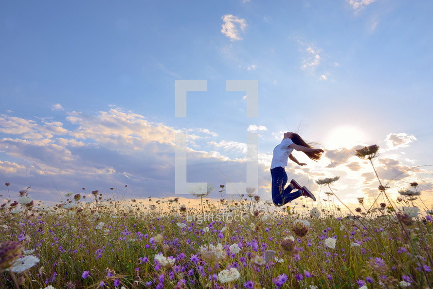 teenage girl jumping in a summer field