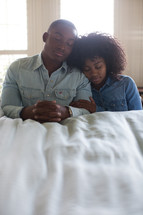 a couple in prayer at the side of a bed 