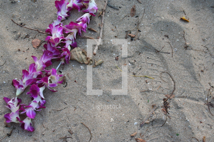 Footprints in the sand near hawaiian lei