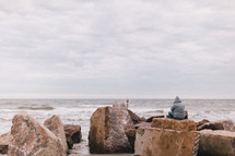 man sitting on rocks at a beach 