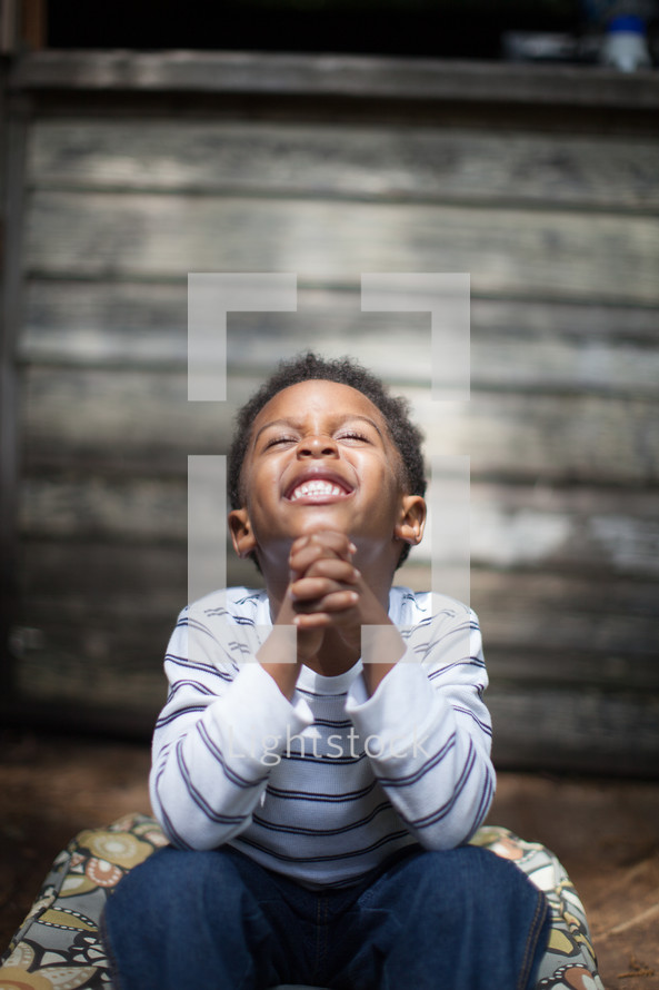 toddler boy with praying hands looking up to God 