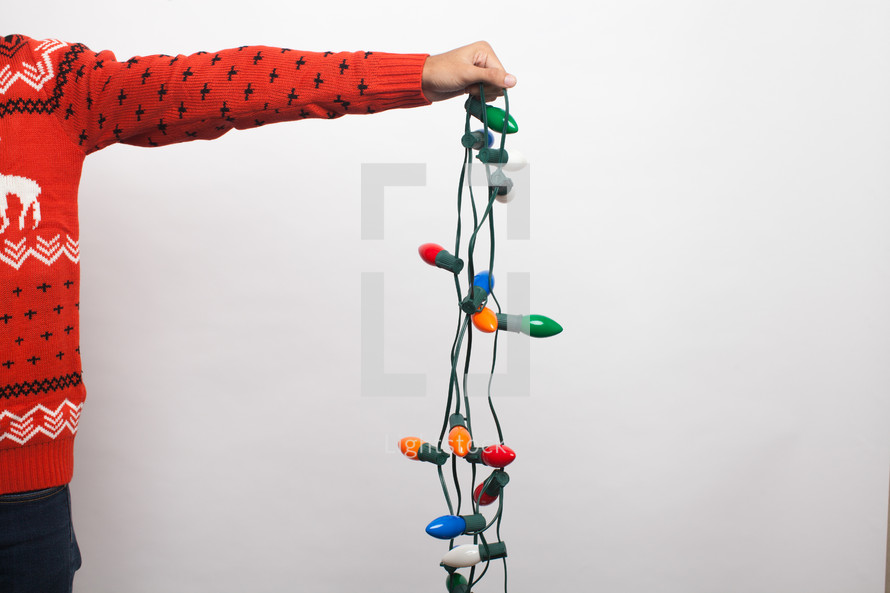 arm holding a string of Christmas lights 