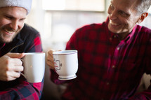 Men smiling and drinking coffee at a Christmas party