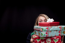 a woman holding a stack of gifts 