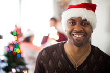A man in a santa hat smiling at a Christmas party
