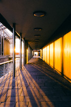 rays of sunlight shining onto pavers in a long covered walkway