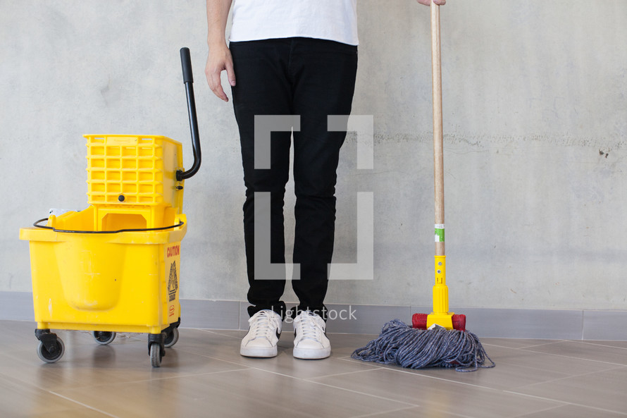 a man standing with a mop and mop bucket 
