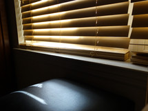 Beige tan blinds with sunlight shining through over window in office or living room