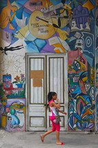 street art painted on an exterior wall and a woman passing by
