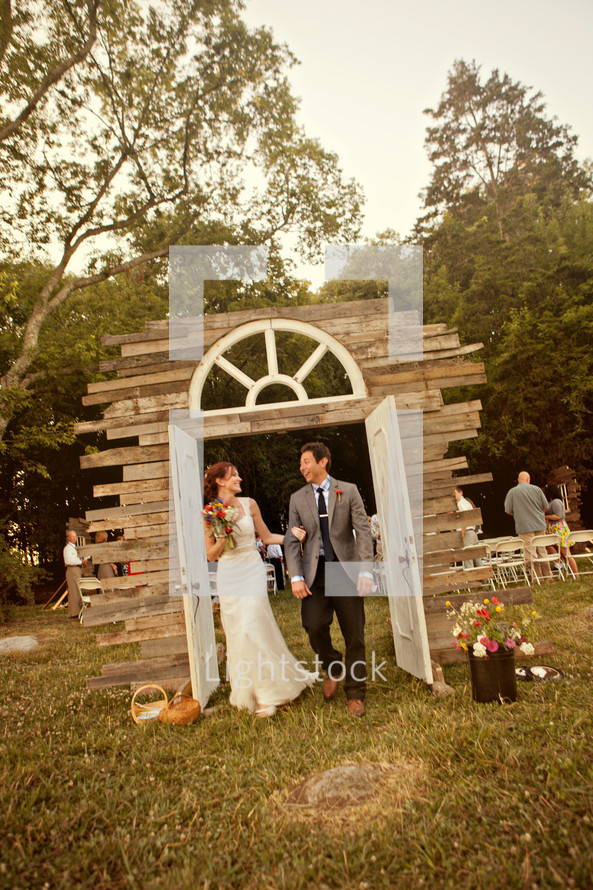 bride and groom walking through doorway arch
