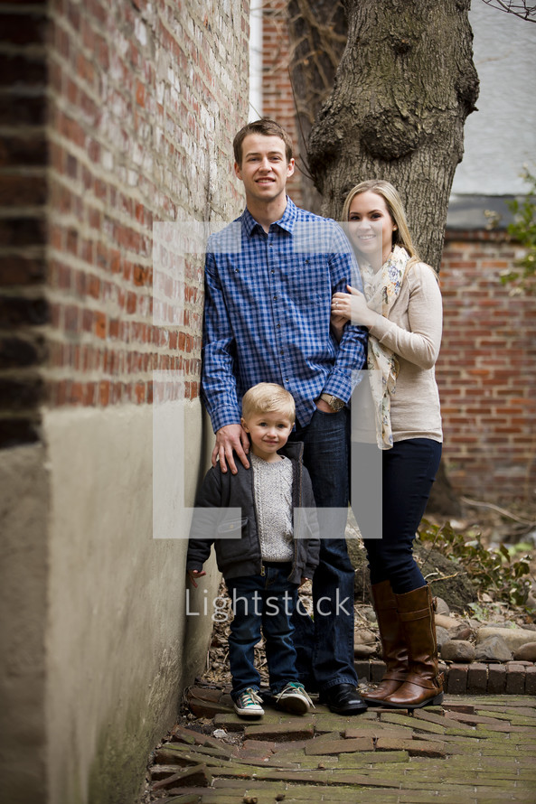 Family standing by a brick wall.