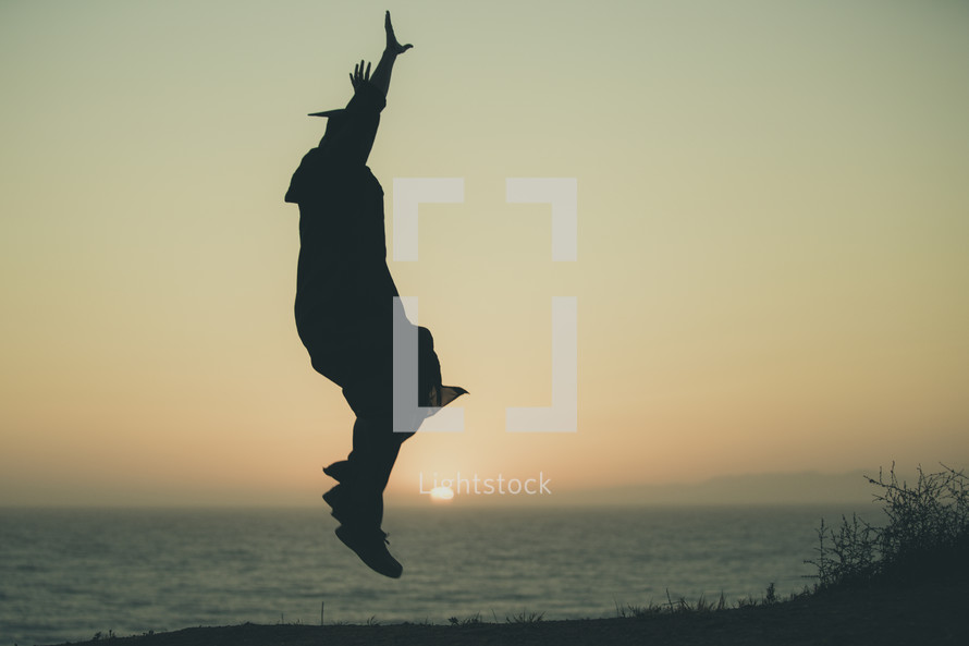 silhouette of a graduate jumping on a beach