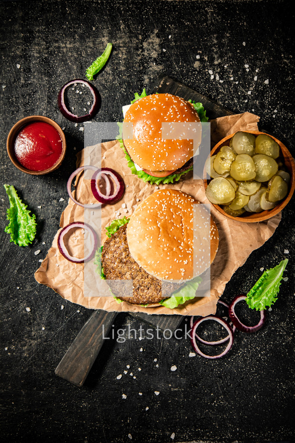 A burger on a stone board on a table. On a black background. High quality photo