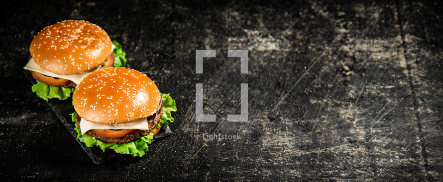 A burger on a stone board on a table. On a black background. High quality photo