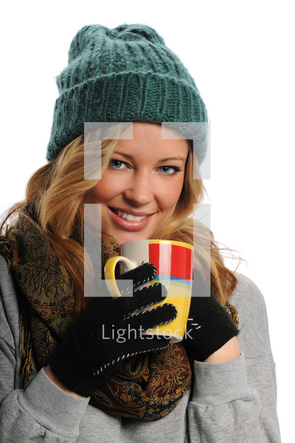 woman in a winter hat, gloves, and scarf drinking hot cocoa 