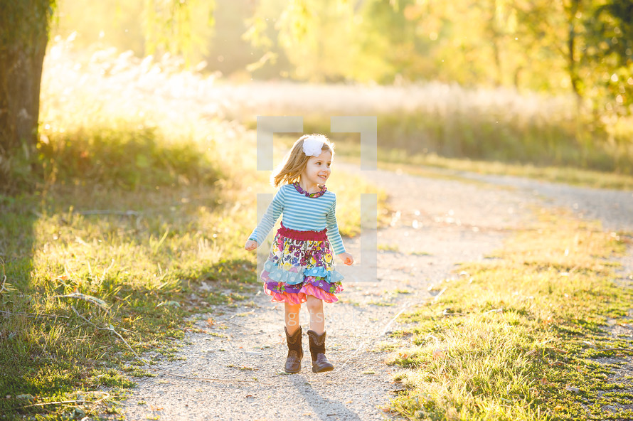 a little girl in a dress and cowboy boots outdoors 
