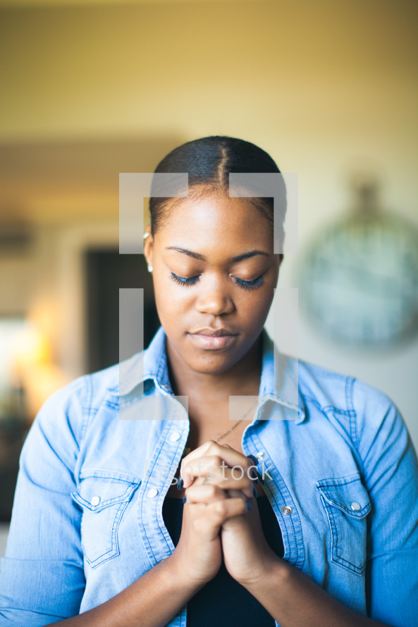 African-American woman with head bowed and praying hands 